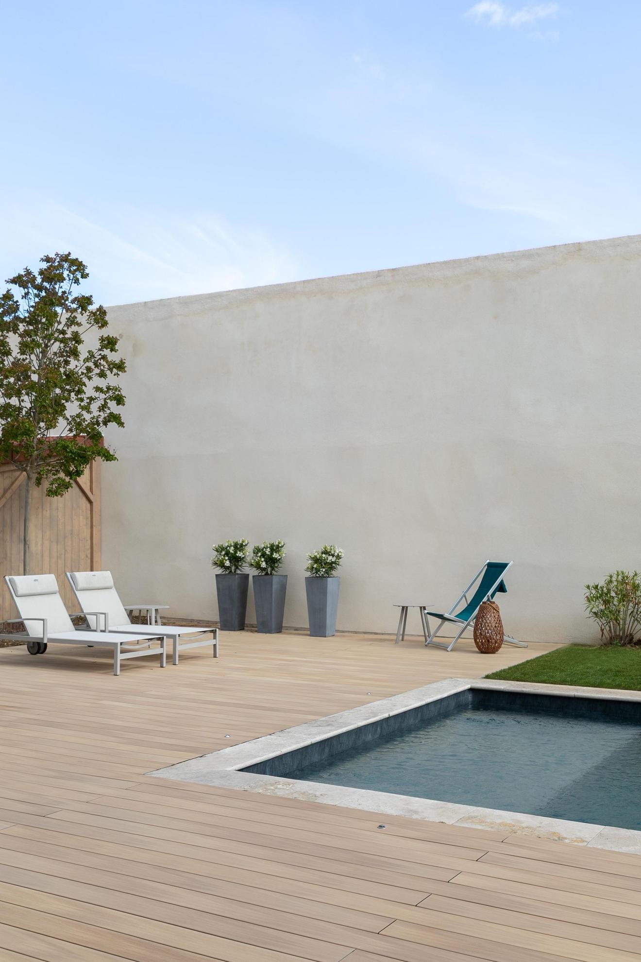 Zwei Liegestühle auf einer Silvadec Nuances Helle Eiche Terrasse mit Pool und Beckenrand
