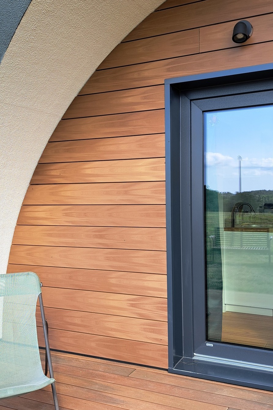 Fassade aus Silvadec Komposit-Holz mit horizontaler Verkleidung an einem modernen Haus, das den Kontrast zwischen Komposit-Holz und anthrazitfarbenen Aluminium-Fensterrahmen hervorhebt