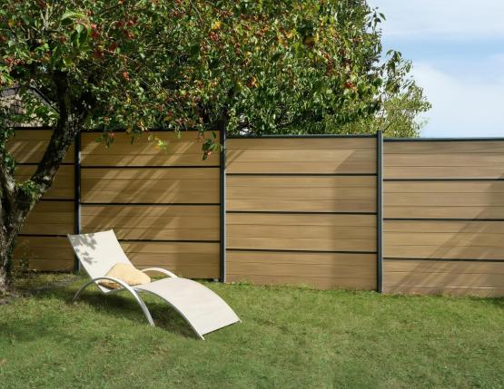 Clôture avec la nouvelle lame coloris nuances chêne clair de Silvadec, bain de soleil en premier plan
