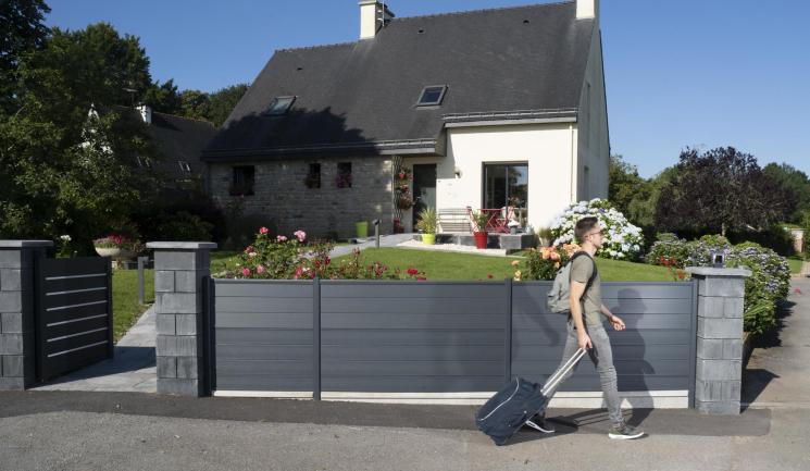 Clôture Atmosphère Silvadec gris anthracite installée devant une maison bretonne avec piliers en pierre et portail moderne